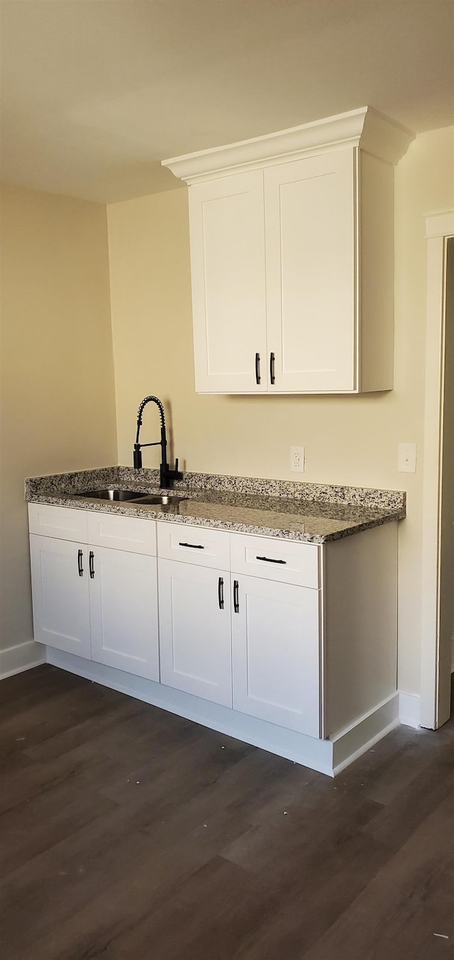 bar with white cabinetry, stone countertops, dark hardwood / wood-style flooring, and sink