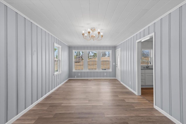 unfurnished dining area with a sink, plenty of natural light, wood finished floors, and a chandelier