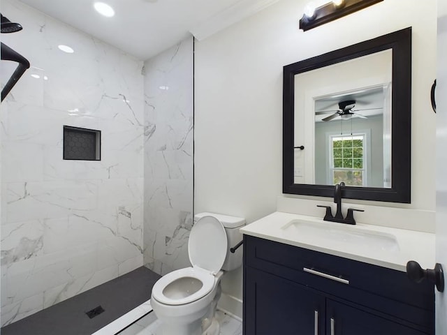 bathroom with ceiling fan, tiled shower, vanity, and toilet