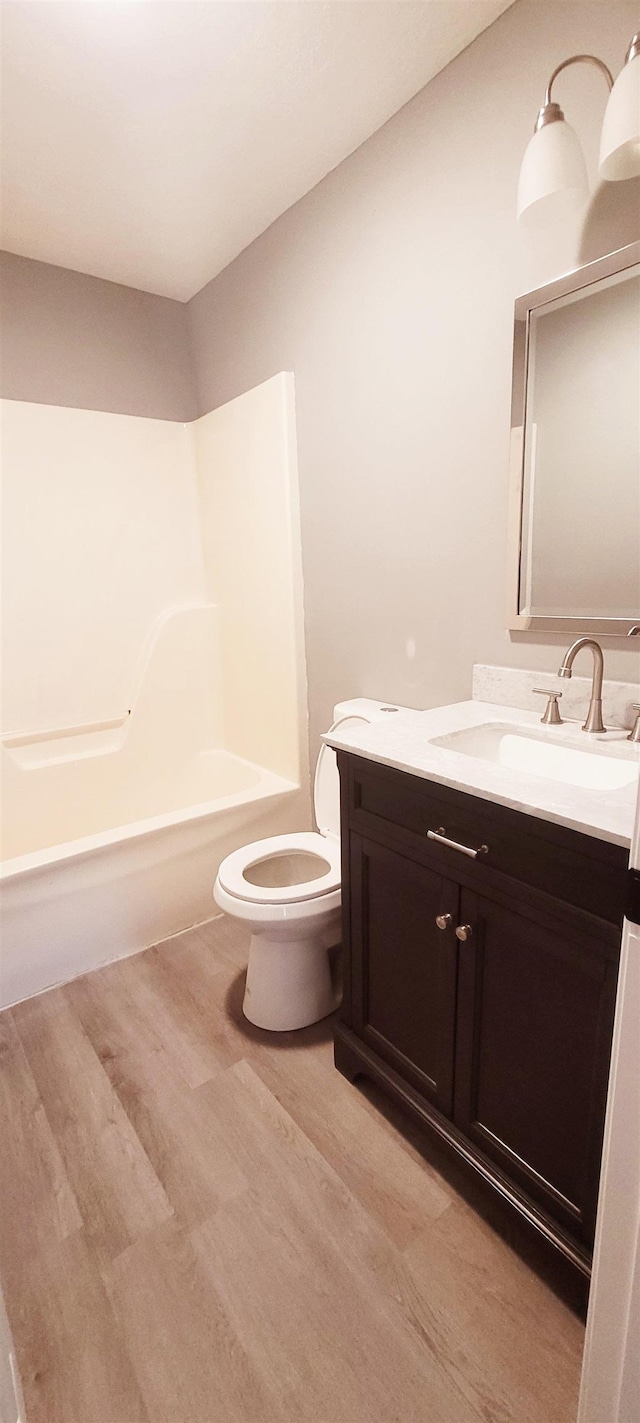 full bathroom featuring vanity, wood-type flooring, shower / bathtub combination, and toilet