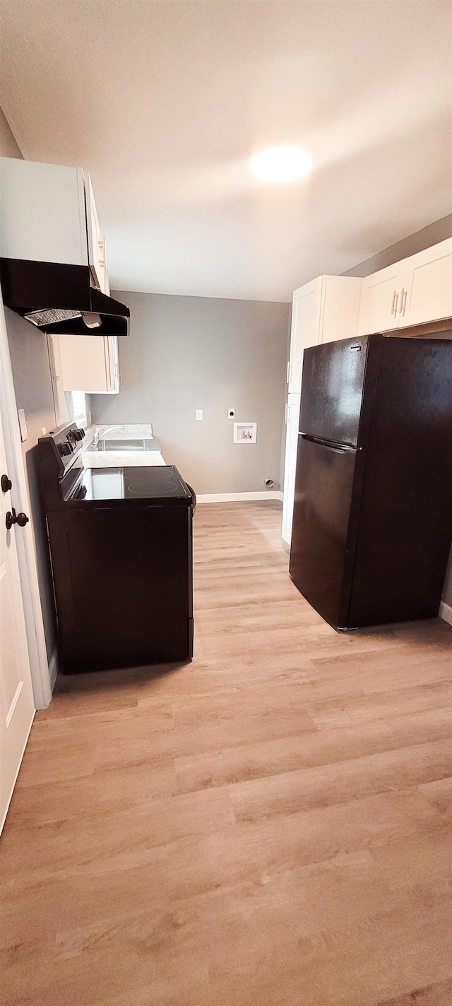 kitchen with black fridge, light hardwood / wood-style flooring, and white cabinets