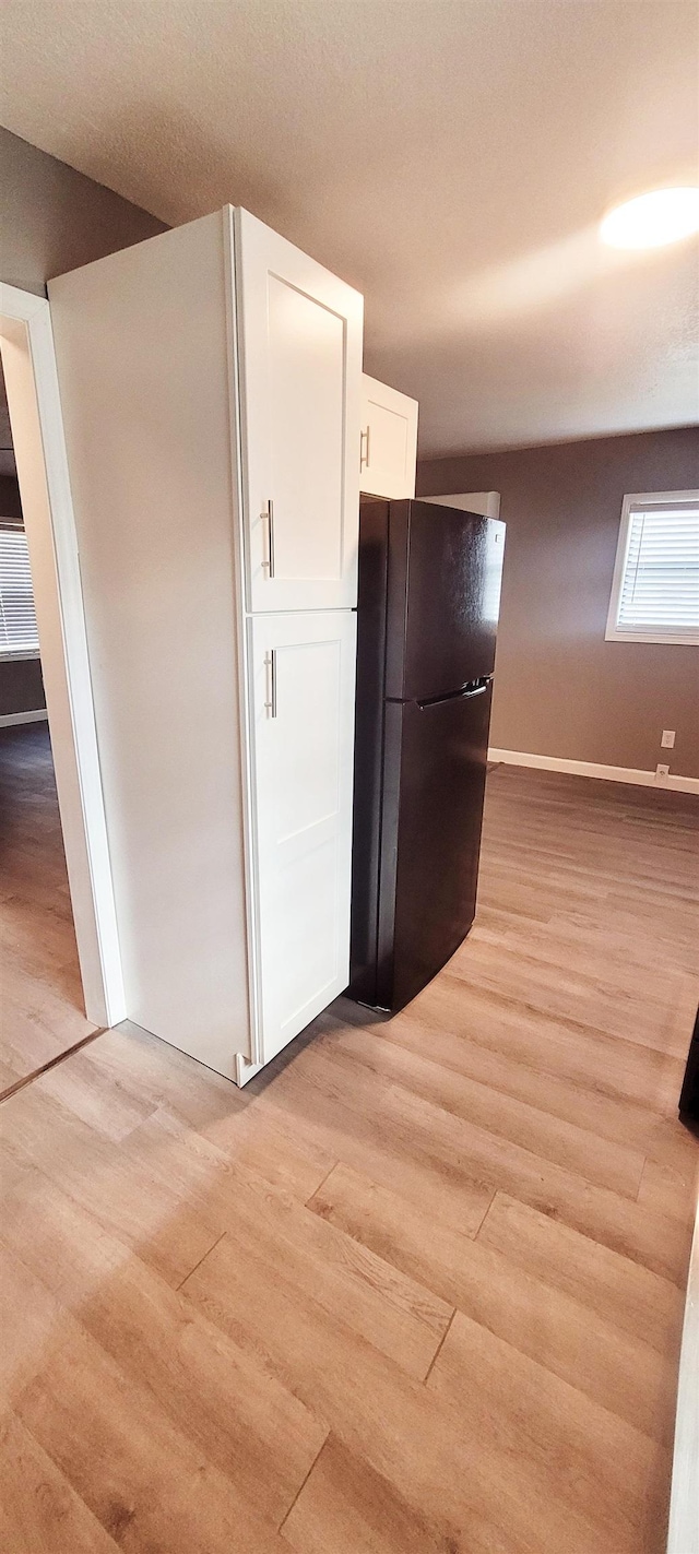 kitchen featuring black refrigerator, white cabinets, and light wood-type flooring