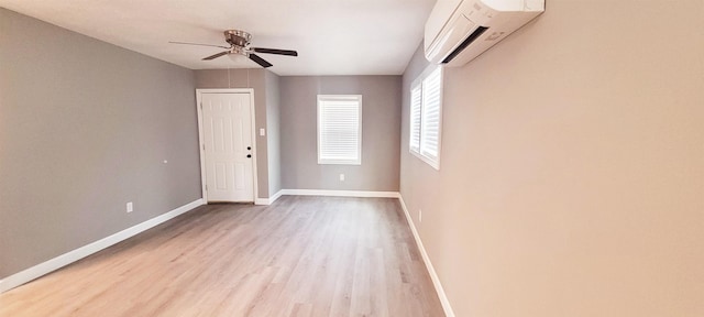 empty room featuring a wall mounted air conditioner, ceiling fan, and light hardwood / wood-style flooring