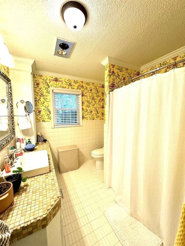 bathroom with crown molding, sink, toilet, a textured ceiling, and tile walls