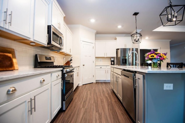 kitchen with tasteful backsplash, white cabinets, stainless steel appliances, and decorative light fixtures