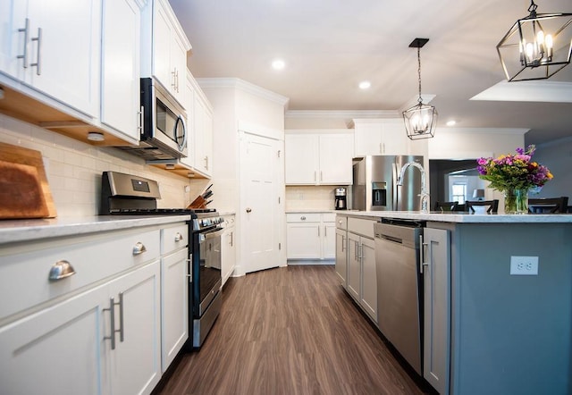 kitchen with pendant lighting, white cabinets, crown molding, appliances with stainless steel finishes, and tasteful backsplash