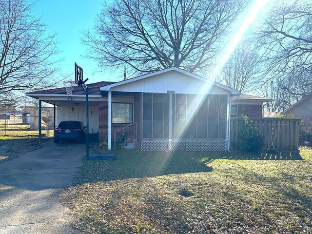 back of property featuring a yard, a carport, and a sunroom