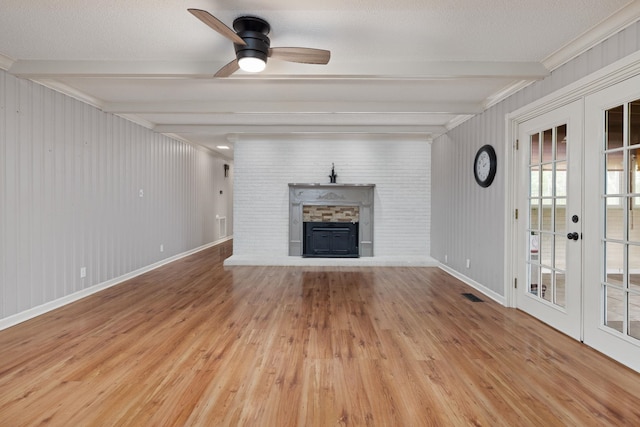  - unfurnished living room featuring a fireplace with raised hearth, beamed ceiling, wood finished floors, french doors, and a ceiling fan