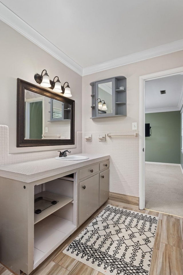  - bathroom with crown molding, vanity, tile walls, and wood finished floors