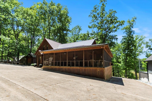  - view of side of property featuring a sunroom, driveway, and metal roof