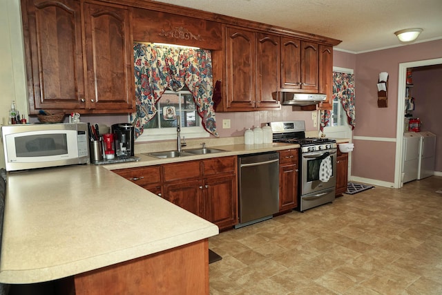 kitchen featuring washer and clothes dryer, stainless steel appliances, a textured ceiling, and sink