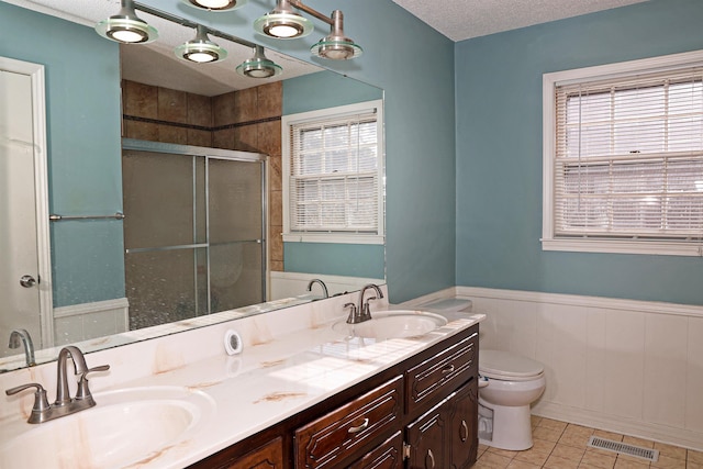 bathroom with walk in shower, vanity, a textured ceiling, tile patterned flooring, and toilet