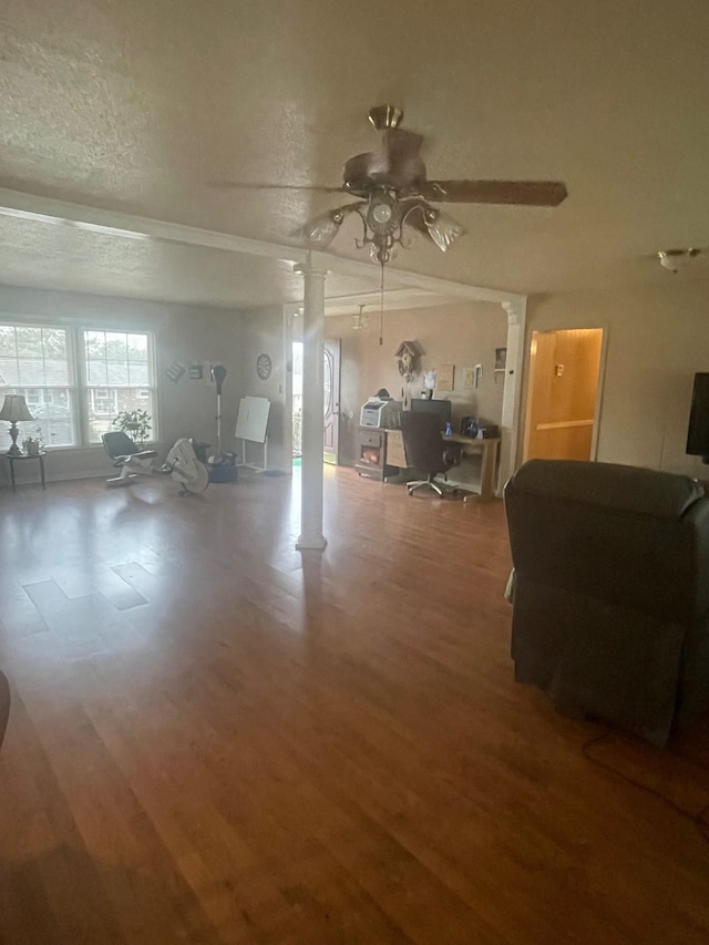 living room with hardwood / wood-style flooring, ceiling fan, a textured ceiling, and ornate columns