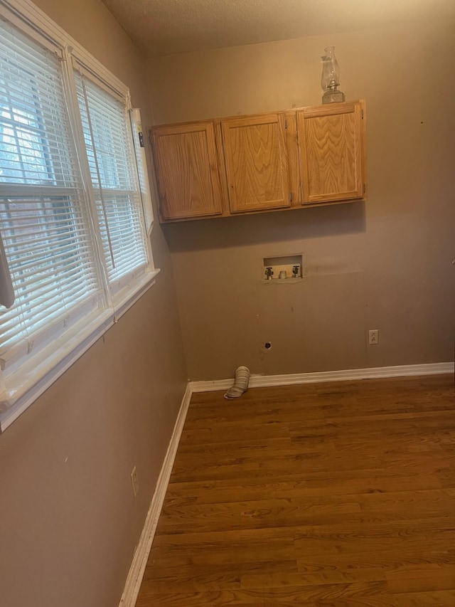 laundry area featuring hookup for a washing machine, hardwood / wood-style flooring, and cabinets