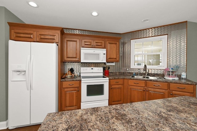 kitchen featuring decorative backsplash, white appliances, crown molding, sink, and dark stone countertops