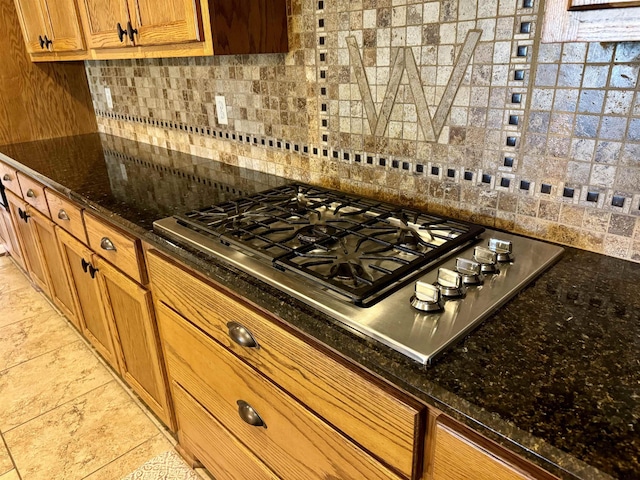 kitchen featuring tasteful backsplash, stainless steel gas stovetop, and dark stone countertops