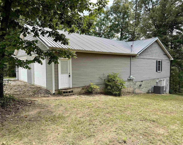 view of side of property with a garage, a lawn, and central air condition unit