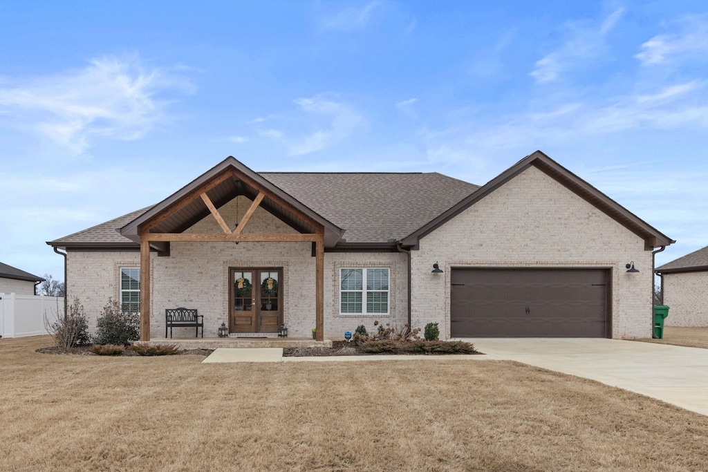 view of front of property with french doors, a garage, and a front lawn