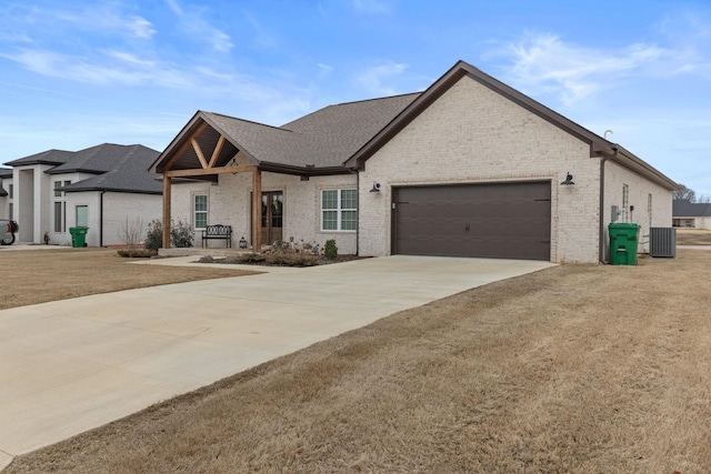 view of front of property with central AC unit, a garage, and a front lawn