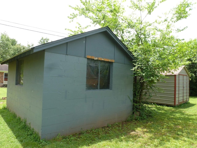 - view of home's exterior with concrete block siding and an outdoor structure