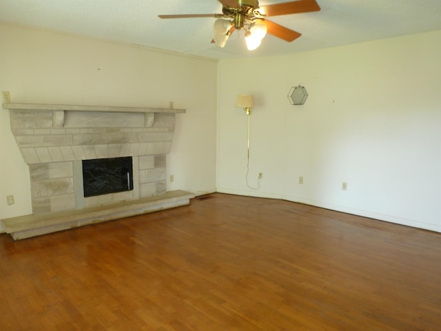  - unfurnished living room featuring wood finished floors, ceiling fan, and a fireplace