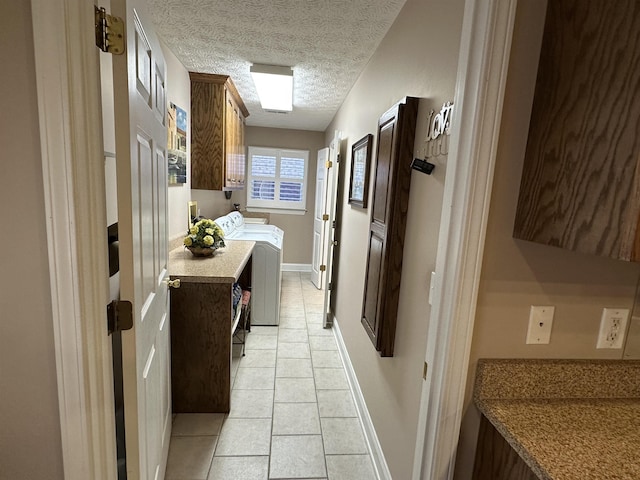 hallway featuring separate washer and dryer, light tile patterned floors, baseboards, and a textured ceiling