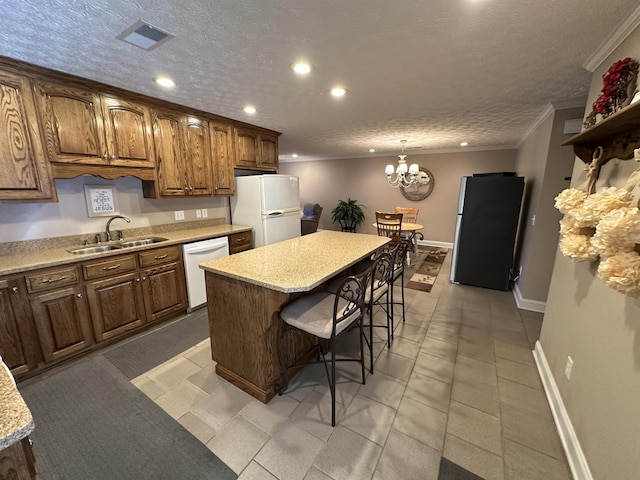 kitchen with a sink, white appliances, ornamental molding, recessed lighting, and light countertops