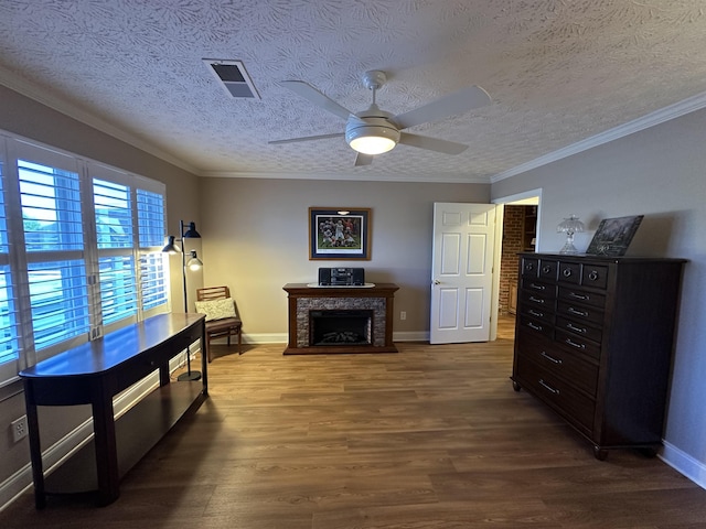sitting room featuring wood finished floors, a ceiling fan, a fireplace, a textured ceiling, and visible vents