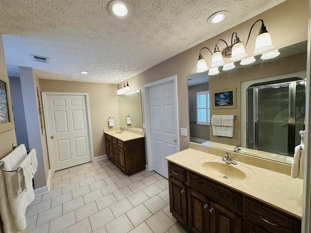 bathroom featuring a stall shower, a sink, two vanities, tile patterned floors, and visible vents