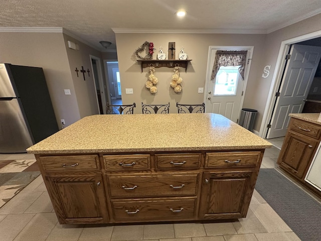 kitchen with freestanding refrigerator, a textured ceiling, crown molding, and a center island