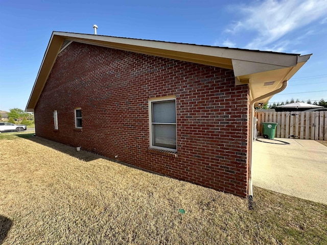 view of side of home with brick siding and fence