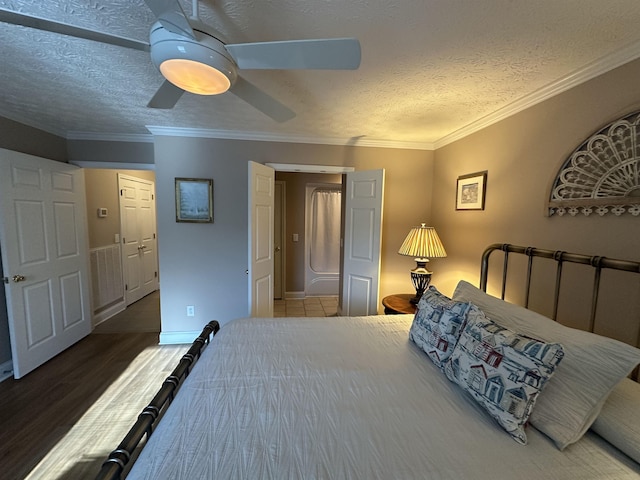 bedroom with wood finished floors, crown molding, a textured ceiling, baseboards, and ceiling fan