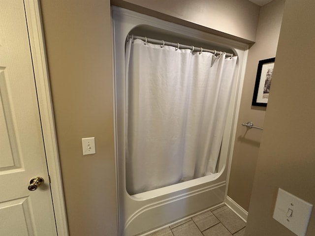bathroom featuring tile patterned floors, baseboards, and shower / bath combo
