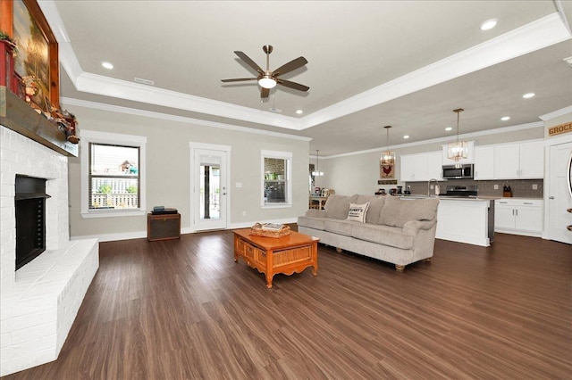 living room with ceiling fan, a fireplace, dark hardwood / wood-style floors, and ornamental molding