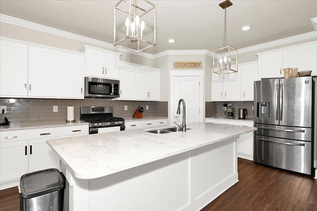 kitchen featuring decorative light fixtures, stainless steel appliances, a center island with sink, and sink