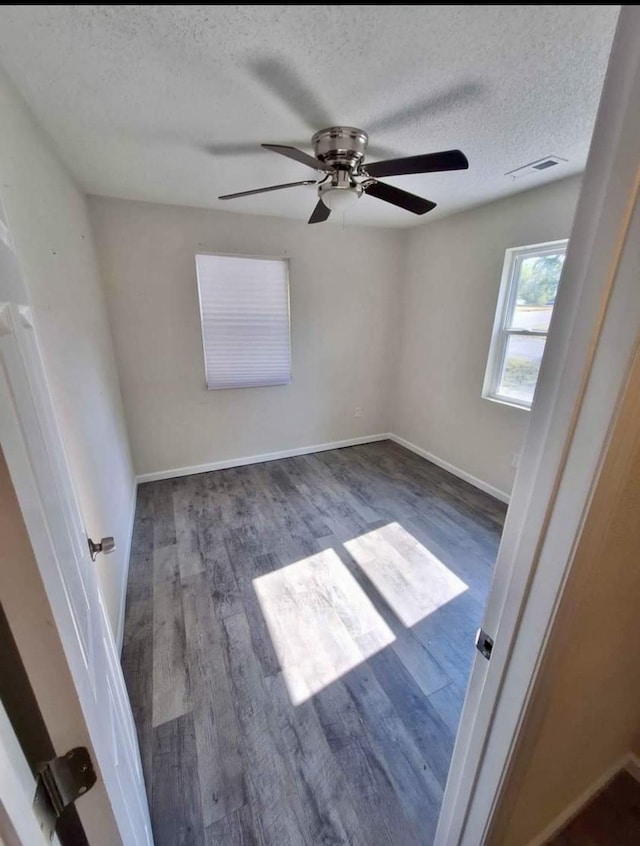 empty room featuring a textured ceiling, ceiling fan, and dark wood-type flooring