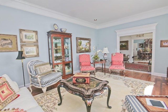 living area featuring baseboards, ornamental molding, wood finished floors, and a notable chandelier