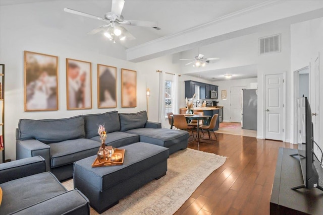 living area featuring beamed ceiling, dark wood-style flooring, visible vents, and a ceiling fan