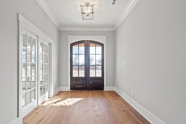 doorway featuring ornamental molding, an inviting chandelier, light wood-type flooring, and french doors