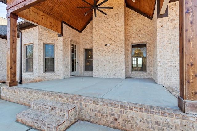 view of exterior entry with ceiling fan and a patio area