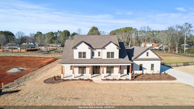  - view of front facade featuring covered porch, a shingled roof, and brick siding