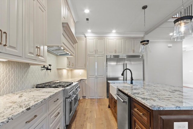 kitchen featuring high end appliances, decorative light fixtures, and white cabinets