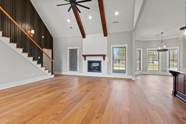 unfurnished living room featuring beamed ceiling, high vaulted ceiling, a large fireplace, and light wood-type flooring