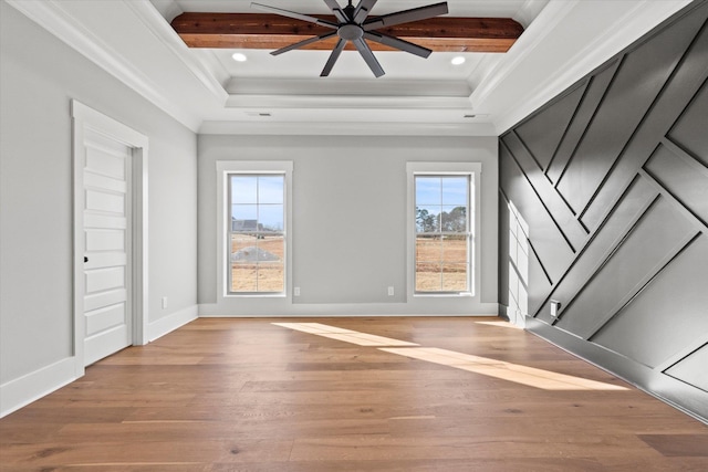 empty room with ornamental molding, beam ceiling, and light wood-type flooring