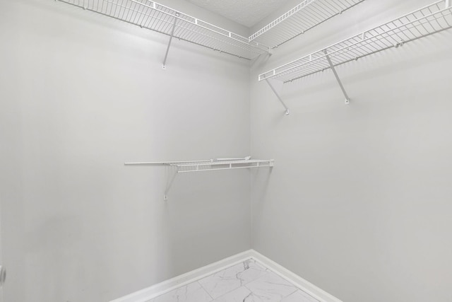  - walk in closet featuring marble look tiles