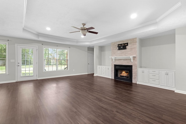  - unfurnished living room with a raised ceiling, crown molding, ceiling fan, dark wood finished floors, and plenty of natural light
