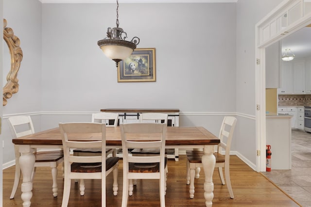 dining area with light wood-type flooring and baseboards