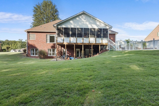 back of house with a sunroom, brick siding, and a lawn