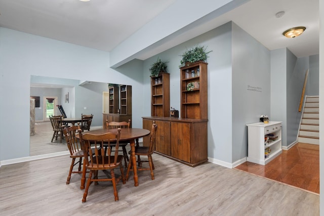 dining space with light wood-style flooring, stairs, and baseboards