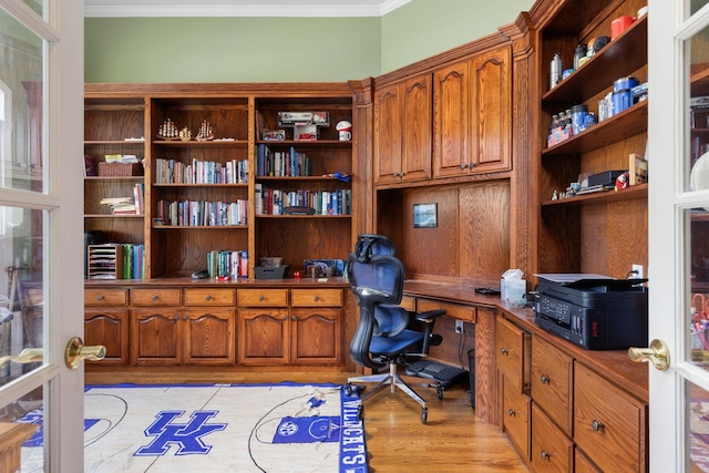 office area with light wood finished floors, french doors, built in desk, and crown molding